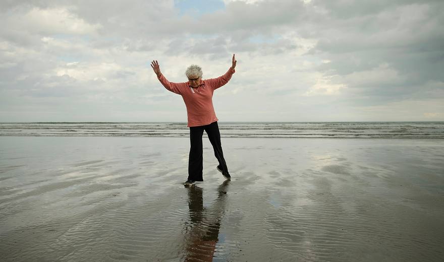 Older woman stretching on a beach
